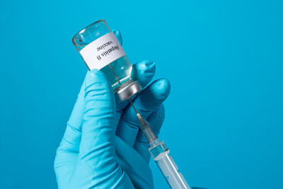 医生或实验室技术员手里拿着一个装有乙肝疫苗的小瓶。在蓝色背景上放置文字。