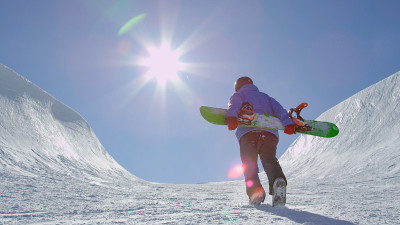 年轻的滑雪板运动员正从雪道中间往山上走