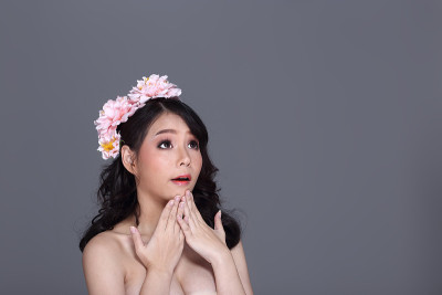 漂亮的亚洲年轻女子与花冠，目前空手掌