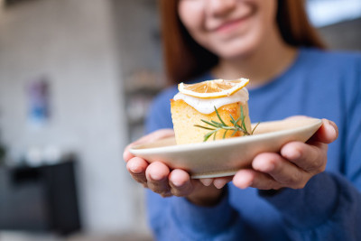 一个年轻女人的特写，拿着一块柠檬磅蛋糕吃