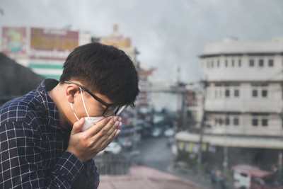 人咳嗽。戴口罩的人因为城市的空气污染
