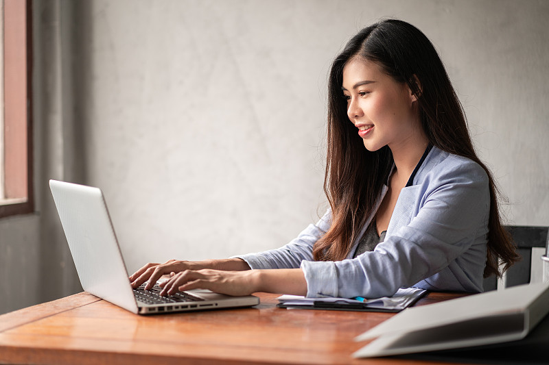 Young happy Asian businesswoman in blue shirt work