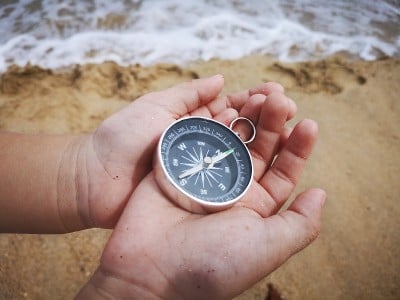 一个小男孩拿着指南针指向北方，面朝大海。