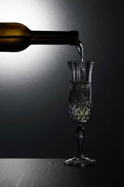 白葡萄酒从瓶子倒进玻璃杯。