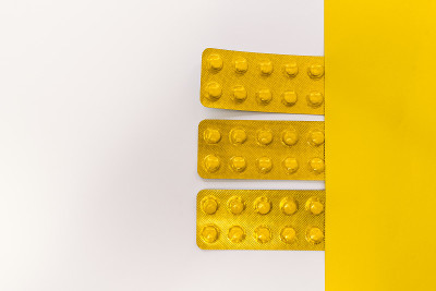 Tablets in packaging on white and yellow backgroun