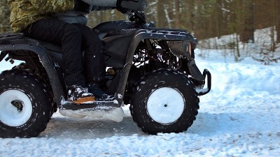 四轮摩托的轮子骑在雪林上