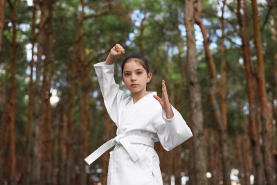 可爱的小女孩穿着和服在森林里练空手道