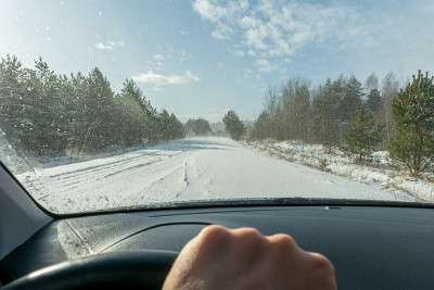 雪林道路在大雪和大风期间。透过汽车的挡风玻璃看到的道路