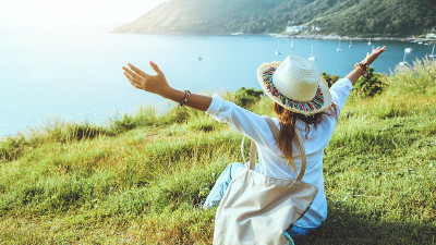 亚洲女人在海滩上旅游自然。旅行放松。坐着看日落。泰国普吉岛的蓬贴角。在夏天。