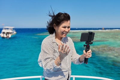 快乐的女人在智能手机上录制视频流，背景是潜水和浮潜的地方