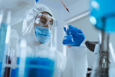 年轻的科学家跌落和摇动生物化学在锥形烧瓶混合和在实验室里看。医生和科学家在covid - 19概念的