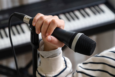 青少年在家庭录音室录音音乐的特写。女孩戴着耳机和麦克风录制歌曲