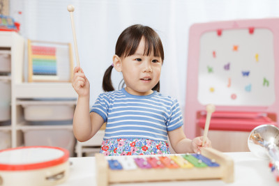 蹒跚学步的小女孩在家里弹奏木琴接受家庭教育