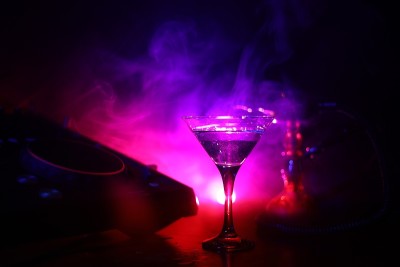 在夜总会的dj控制器上放着杯里有橄榄的马提尼酒。Dj控制台与俱乐部饮料在音乐派对在夜总会迪斯科灯。