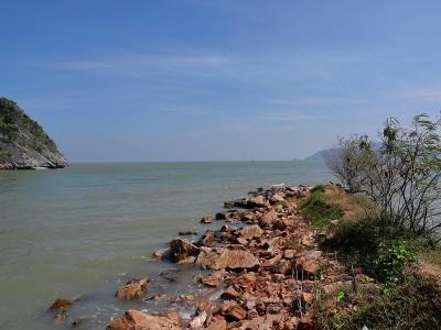 碧绿的海水里的礁石和石头，背景是山和岛