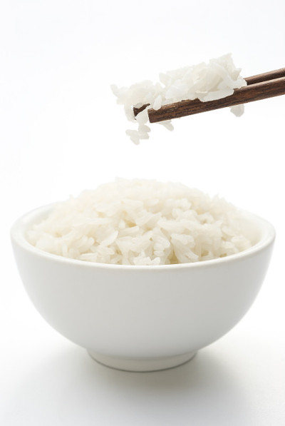米饭和筷子放在白色的夹道上，垂直构成