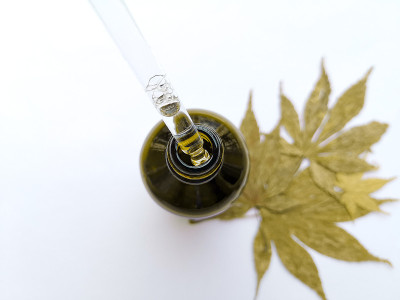 在叶子白色的背景上，用吸管从瓶中吸出液体油