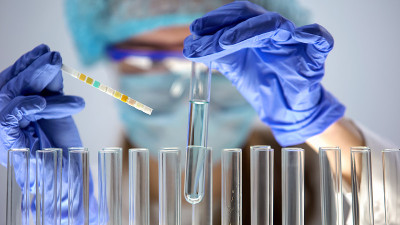 实验室工作人员手持蓝色液体管测量酸度水平，进行科学研究