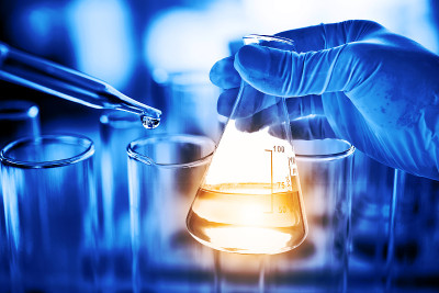 有实验室玻璃器皿背景的科学家手上的烧瓶。科学或化学研究与发展的概念。