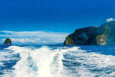 摩托艇在热带海上泡沫和波浪，岩石岛在右侧