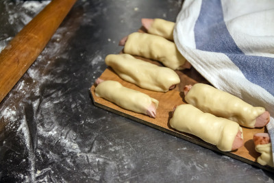 在烘烤之前准备好的生香肠放在餐巾下面。概念,家庭烹饪