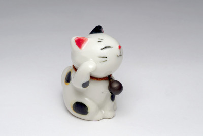 微笑招手的猫或Maneki Neko在日本孤立的白色背景。
