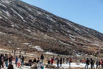 黑山下有雪，游客在地上有棕色的草，雪和结冰的池塘在冬天在零点拉冲。北锡金,印度。