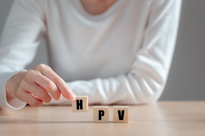 人类乳头瘤病毒(HPV)的缩写在木块上，亚洲妇女持有木块，病毒一些菌株感染生殖器，可导致宫颈癌。女性