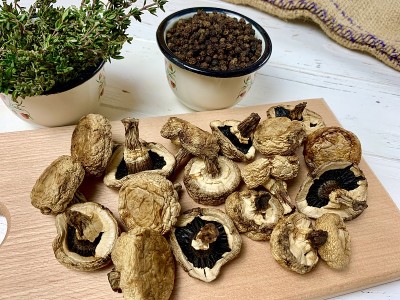 白木桌上的切菜板上放着干蘑菇和百里香和黑胡椒