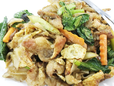 木桌上白底豆沙炒面和猪肉。泰国风格的食物。