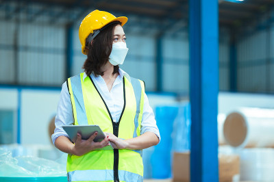 总工业工程师视察口罩厂。在使用笔记本电脑的时候画一个女人的肖像。他们表现出一种自信的态度。危险区域的