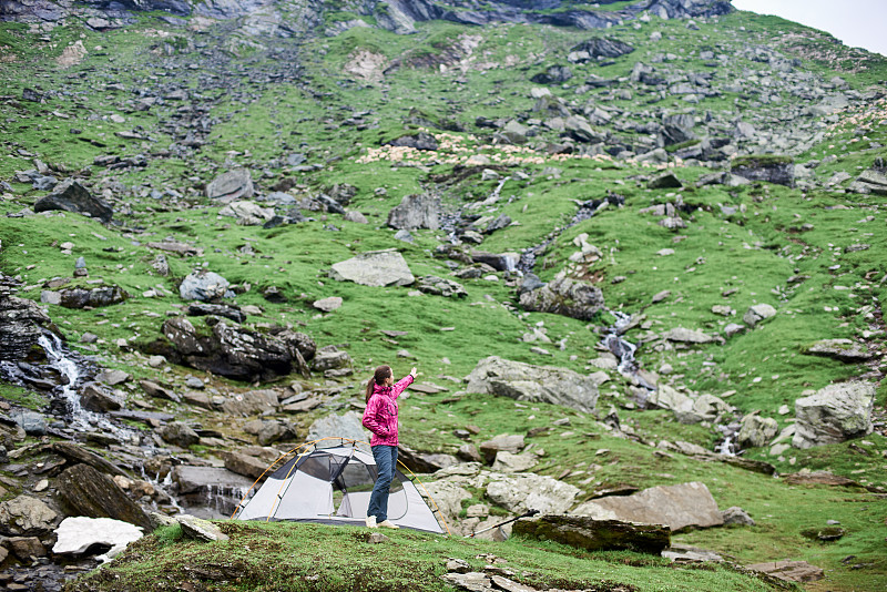 女人徒步者站在她的帐篷附近在山谷指向copyspace探险者探索旅行者旅行旅游娱乐活跃的运动女人爱好