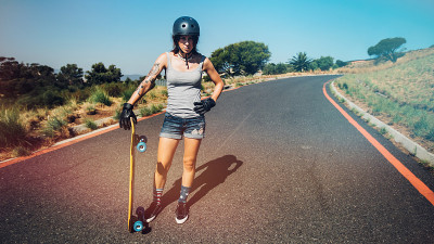一个骑着长板在乡村公路上的年轻女子