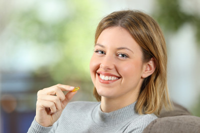 拿着维生素片的女人看着摄像机