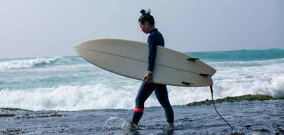 女冲浪手拿着冲浪板去冲浪大浪