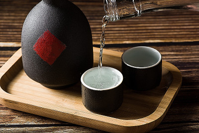 中国白酒，烈酒饮料从一个瓶子倒进一个玻璃杯的木材背景
