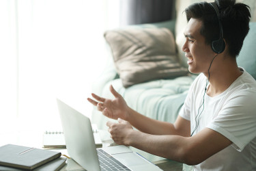 亚洲年轻的学生男子企业家戴耳机工作通过视频电话会议学习在家在线学习。电子学习研讨会会议。新冠肺炎大流