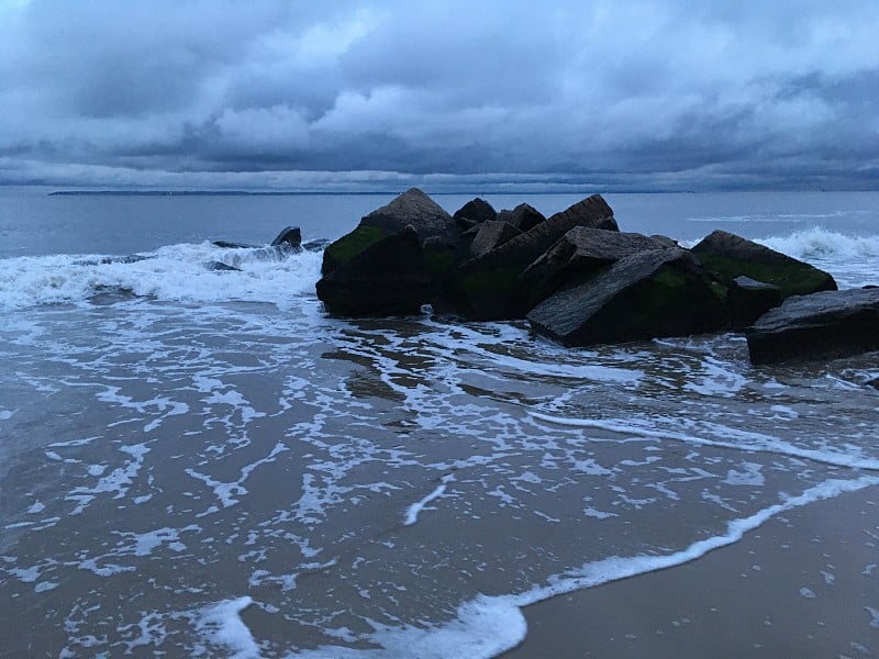 在春天阴天下雨后的康尼岛海滩日落在布鲁克林，纽约，纽约。