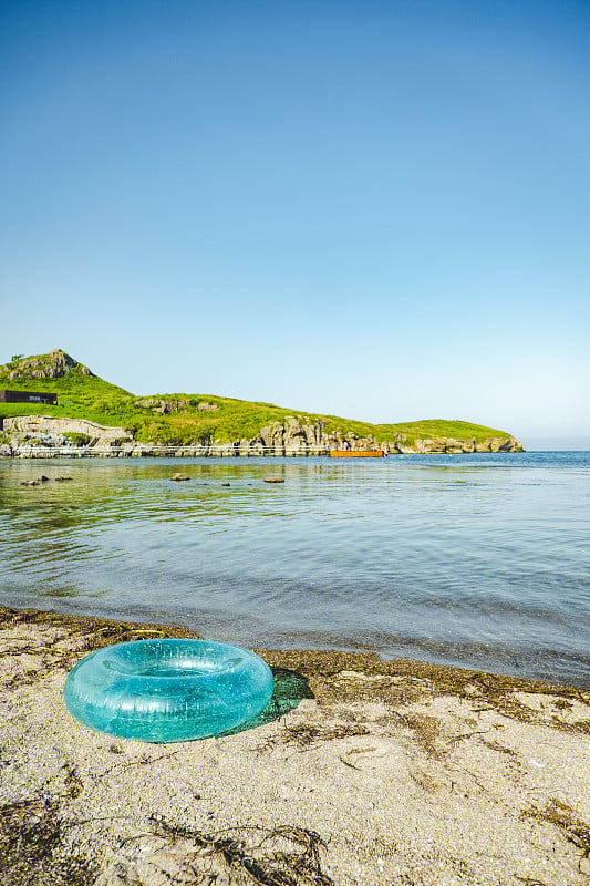 在美丽透明的大海附近的沙滩上游泳的绿宝石充气圈。夏季水上娱乐。有选择性的重点