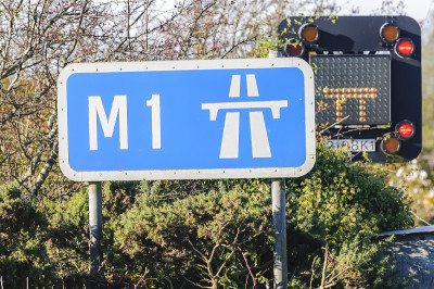 M1高速公路标志后面的道路封闭标志显示双车道因事故关闭。