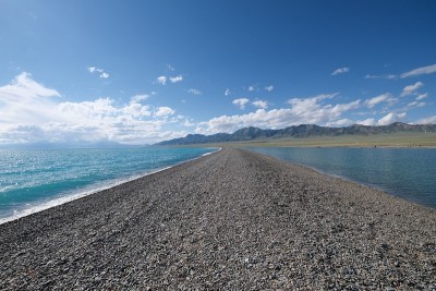 在阳光明媚的日子里，美丽的蓝色海水之间空石路地面