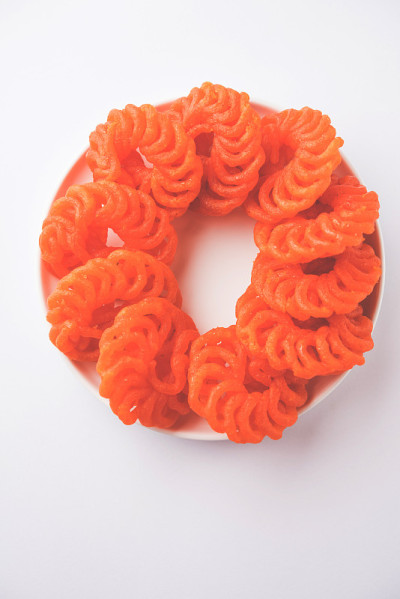 在白色的背景上，用白色的陶瓷盘子盛着印度甜的Imarti或Jalebi