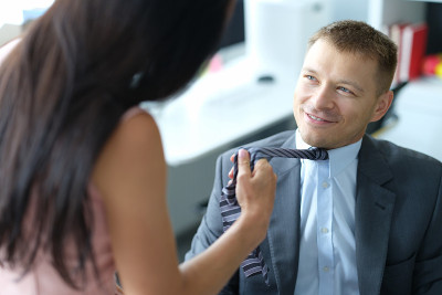 女人勾引和拉年轻的微笑老板的领带