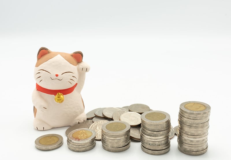 日本财富猫的数字(Maneki Neko)与堆叠的硬币