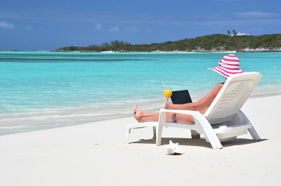 在热带海滩上拿着笔记本电脑的女孩。Exuma,巴哈马群岛