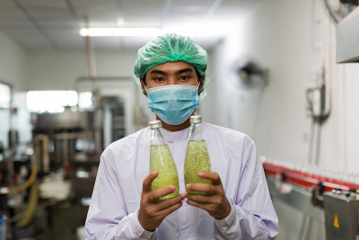 饮料厂男工人拿着装着罗勒籽和菠萝的瓶子。食品制造商、分销商和供应商的概念