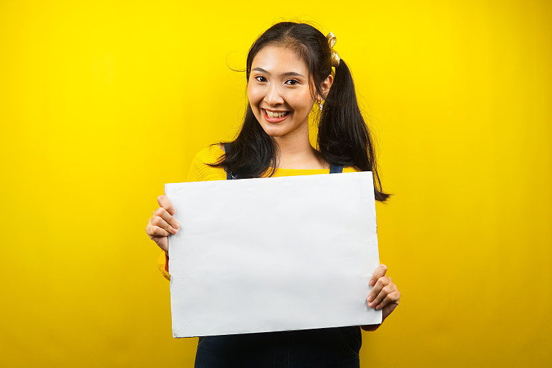 漂亮可爱的年轻女子欢快地拿着空白的空横幅、广告牌、白板、白板招牌、白色广告牌，在文案空间展示东西，促