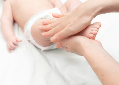 女人用手给新生儿做腿部按摩。宝宝按摩
