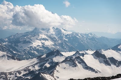 深蓝的天空和云在岩石山峰上覆盖着冰川和雪