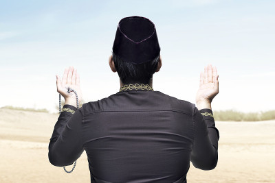 后视图亚洲穆斯林男子祈祷与念珠在他的手上